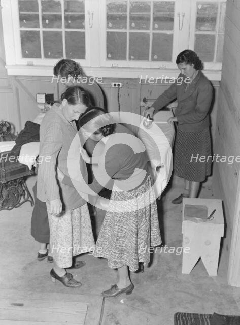 Camper receives help in fitting a coat from WPA sewing instructor, FSA, California, 1938. Creator: Dorothea Lange.