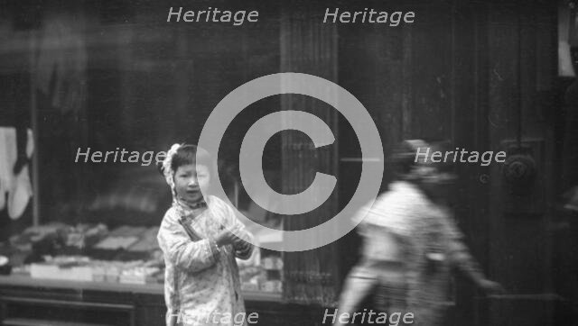 Young girl walking down the street, looking into the camera, Chinatown, San Francisco, c1896-1906. Creator: Arnold Genthe.