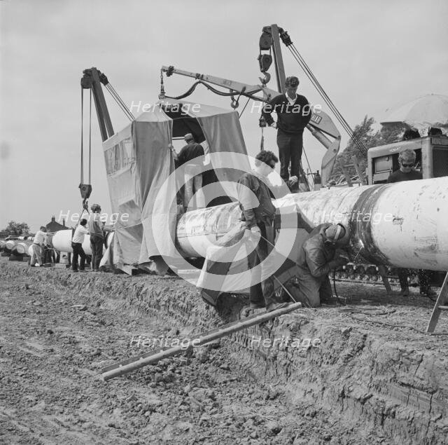A team of men working on the lining up operation of the Fens gas pipeline, Norfolk, 24/07/1967. Creator: John Laing plc.
