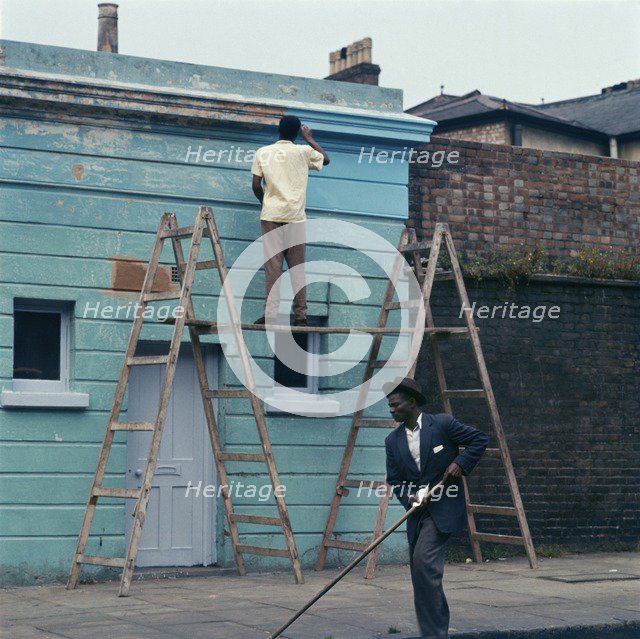 Man re-painting the exterior of a business premises in Kentish Town, London. 1960s. Artist: John Gay.