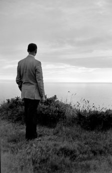 The silhouette of a man standing on a cliff top watching the sunset over the sea, c1945-c1965. Artist: SW Rawlings