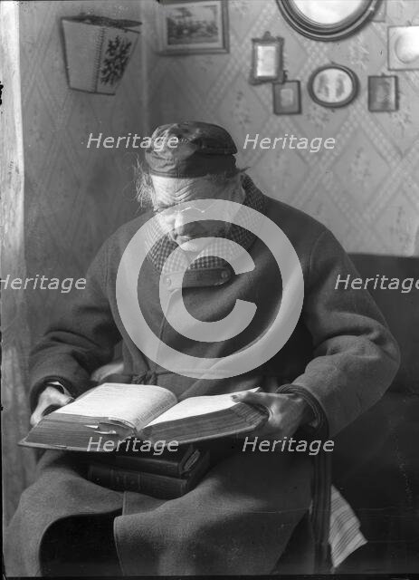 An elderly man sits and reads a book, 1880-1910. Creator: Johan Severin Nilson.
