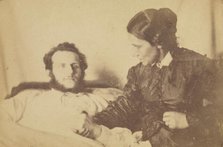 A bearded man lying in bed, his hand held by his wife who is seated next to the bed, 1870-79. Creator: Unknown.
