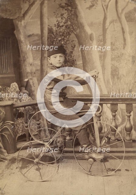 A boy on a bicycle in a photo studio, 1880. Creator: Unknown.