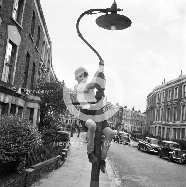 Boy climbing a lamppost, Kentish Town, London, 1960-1965. Artist: John Gay