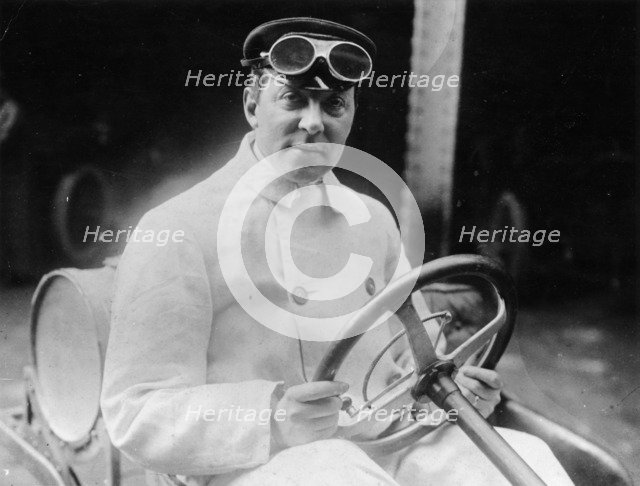 A man at the wheel of his car dressed in a driving coat and goggles. Artist: Unknown