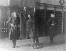 Female students exercising, one with a wall-mounted device using ropes..., Washington, D.C., (1899?) Creator: Frances Benjamin Johnston.