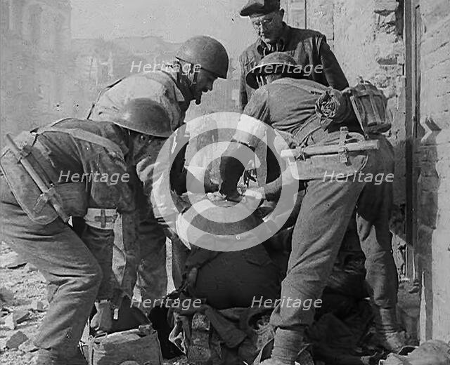 British Medics Helping a Fellow Soldier, 1943-1944. Creator: British Pathe Ltd.