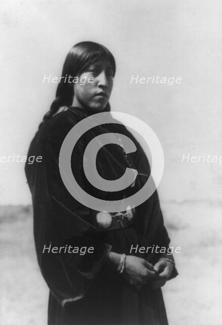 Arapaho maiden, three-quarter-length portrait, standing, facing right, c1910. Creator: Edward Sheriff Curtis.