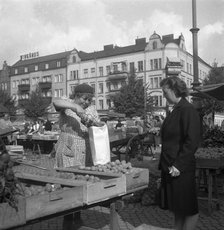 Woman buying potatoes from a fruit and vegetable stall in the market, Malmö, Sweden, 1947. Artist: Otto Ohm