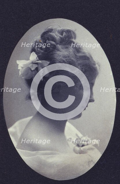 Oval portrait of woman with a flower in her hair and a corsage on her dress, c1900. Creator: Fannie L. Elton.