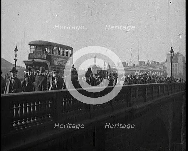 Pedestrians And Commuters Crossing London Bridge With Buses in the Background, 1920s. Creator: British Pathe Ltd.