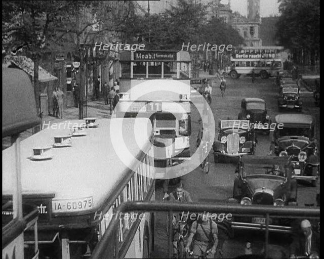 Buses, Cars and People on Bikes Driving Down the Road, 1933. Creator: British Pathe Ltd.