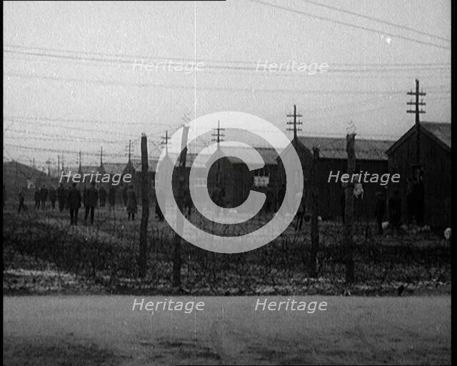 Irish Prisoners Walking Across a Barbed Wire Fenced Prison Ground, 1921. Creator: British Pathe Ltd.