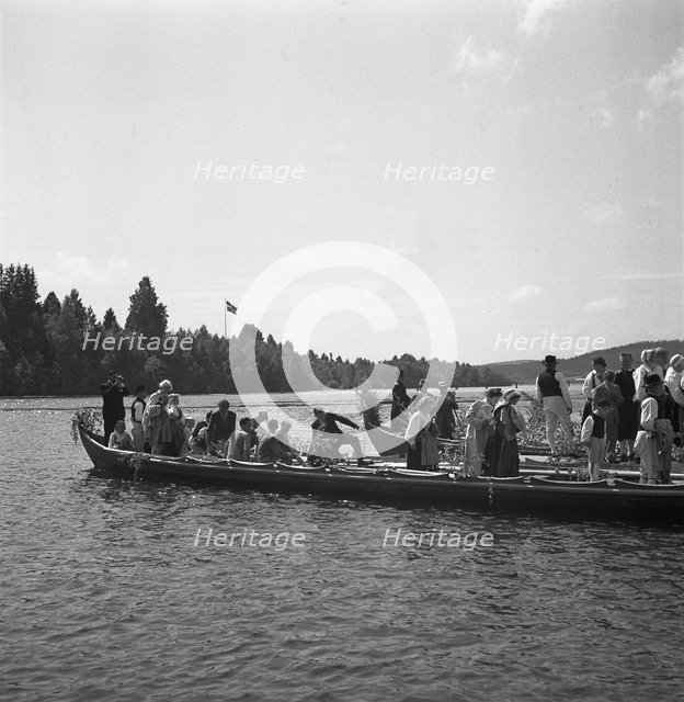People arrive in long boats, called church boats, for the Midsummer celebrations, Sweden, 1941. Artist: Torkel Lindeberg