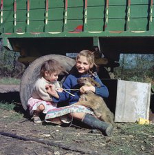 Two young gipsy girls playing with a dog, Charlwood, Newdigate area, Surrey, 1964.