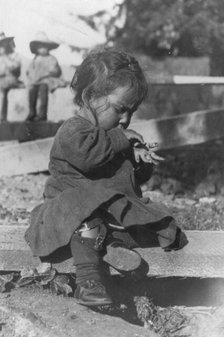 Young Eskimo child seated on board, between c1900 and c1930. Creator: Unknown.