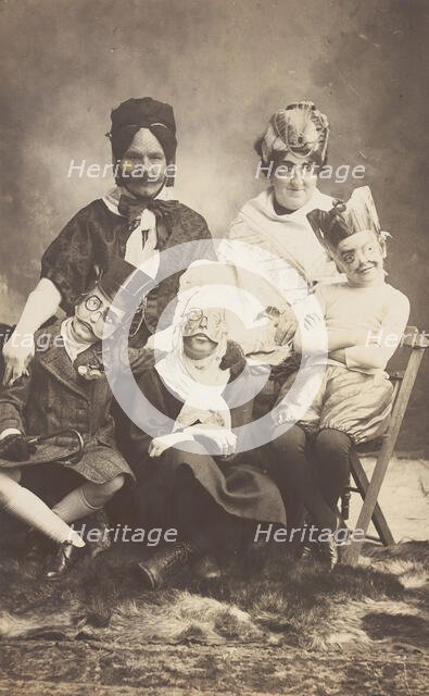 A family, all members wearing grotesque masks, the father in drag, c1910. Creator: Unknown.