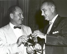 T. Keith Glennan shows Lyndon Johnson aluminized mylar flim used to make the Echo I balloon, 1960.. Creator: NASA.