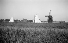 Two yachts under sail seen over the reed beds near East Tunstall Mill, Norfolk, 1934.  Artist: HES Simmons