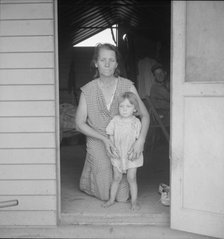 Migrant mother and child at doorway of steel shelter, FSA camp, Tulare County, 1939. Creator: Dorothea Lange.