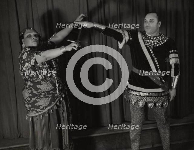 Minto Cato as Azucena and Parker Watkins as Manrico, swearing vengeance on a sword, 1936. Creator: Eagle Ezzes & Mipaas.