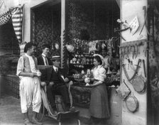 Pan-American Exposition, Buffalo, N.Y., 1901: Man in wheeled chair at souvenir shop with 4..., 1901. Creator: Frances Benjamin Johnston.