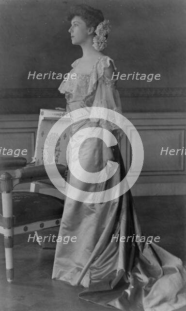 Alice Roosevelt Longworth, full-length portrait, standing next to chair, facing left, 1903. Creator: Frances Benjamin Johnston.