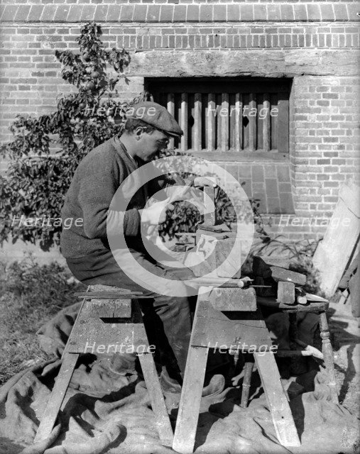 A craftsman shaping a brick on a bench at Great Dixter, Northiam, East Sussex, 1919. Artist: Nathaniel Lloyd