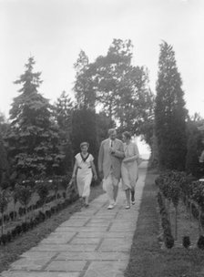 Edge, Charles N., walking with Margaret Edge and another woman in his garden, 1932 or 1933. Creator: Arnold Genthe.