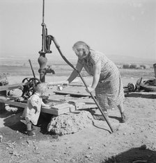 Mrs. Soper with youngest child at the well, Willow creek area, Malheur County, Oregon, 1939. Creator: Dorothea Lange.