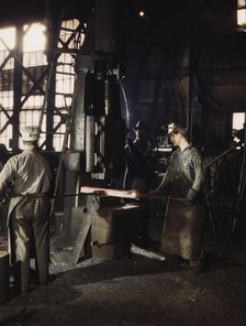 Working with a small steam drop hammer, blacksmith shop, Santa Fe RR shops, Topeka, Kansas, 1943. Creator: Jack Delano.