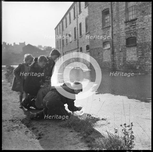 Children using a goldfish bowl to fish in the Caldon Canal, Hanley, Stoke-on-Trent, 1965-1968. Creator: Eileen Deste.