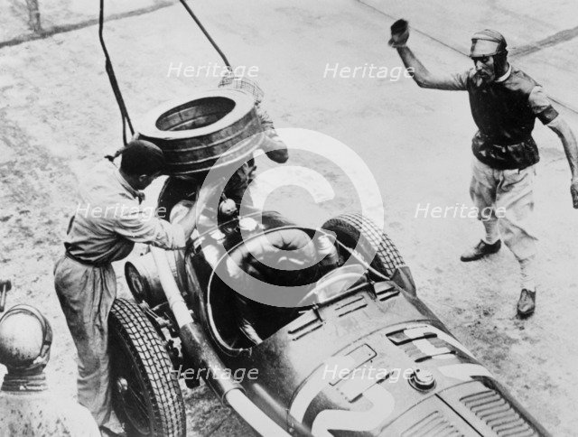 Tazio Nuvolari waiting for his car to be refuelled, c1930s(?). Artist: Unknown