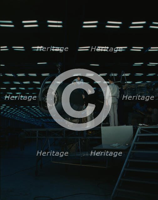 Lowering an engine in place in assembling...Consolidated Aircraft Corp..., Fort Worth, Texas, 1942. Creator: Howard Hollem.