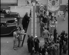 Bud Flanagan With a Frying Pan Climbing a Ladder Resting Against Coronation Decorations in..., 1937. Creator: British Pathe Ltd.