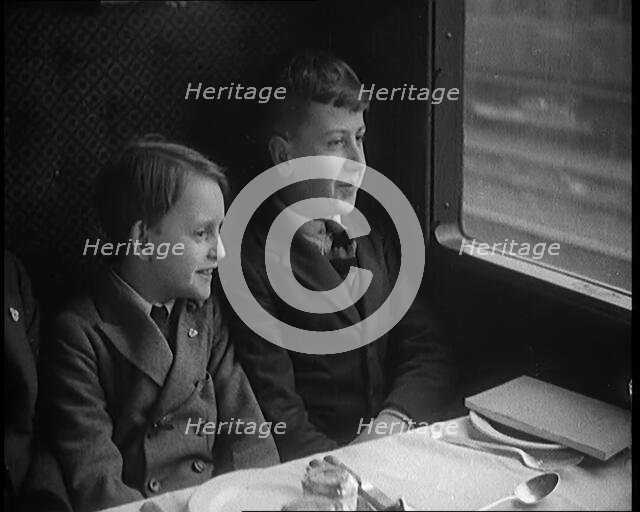 Two Male Children in a Train Carriage Sitting in Front of a Table Laid for a Meal, 1931. Creator: British Pathe Ltd.
