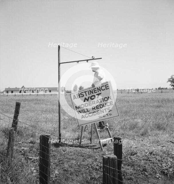 Member of the committee...erects sign on U.S. 99 highway, near Hanford, California, 1939. Creator: Dorothea Lange.