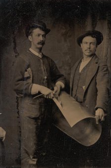 Two Tinsmiths Cutting a Curled Sheet of Metal, 1880s. Creator: Unknown.