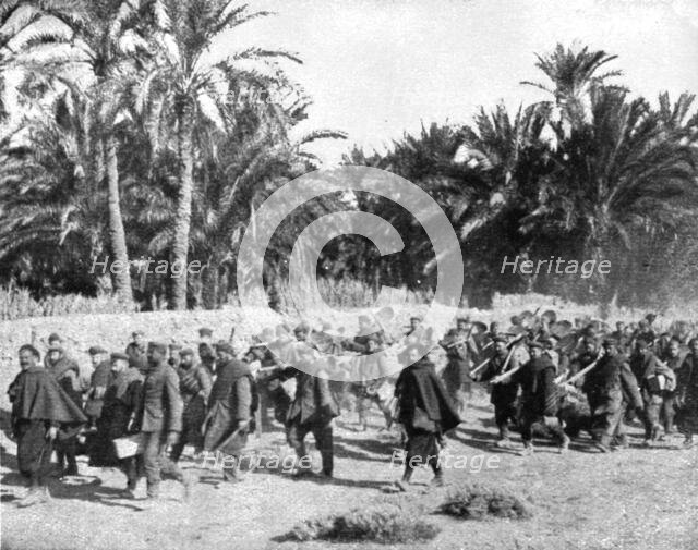 'Tandis que.; Voici des prisonniers allemands traversant une riante oasis algerienne pour..., 1917 Creator: Unknown.