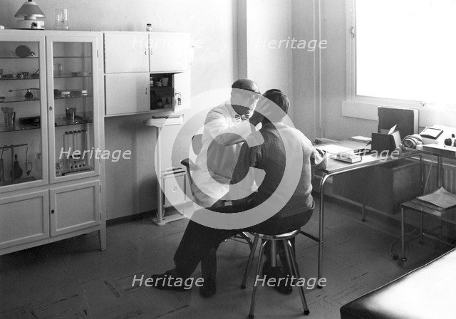 A worker at Trelleborgs rubber factory consulting the works doctor, Trelleborg, Sweden. Artist: Unknown