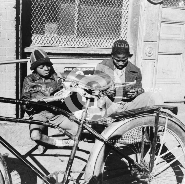 Two Negro boys reading the funnies on a doorstep, Washington, D.C., 1942. Creator: Gordon Parks.