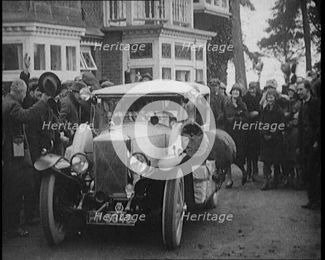 Two Female Civilians Explorers Driving Away in Their Heavily Loaded Car Watched by a Small..., 1920. Creator: British Pathe Ltd.