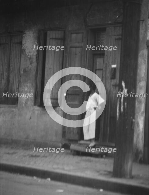 Woman standing in a doorway in the French Quarter, New Orleans, between 1920 and 1926. Creator: Arnold Genthe.