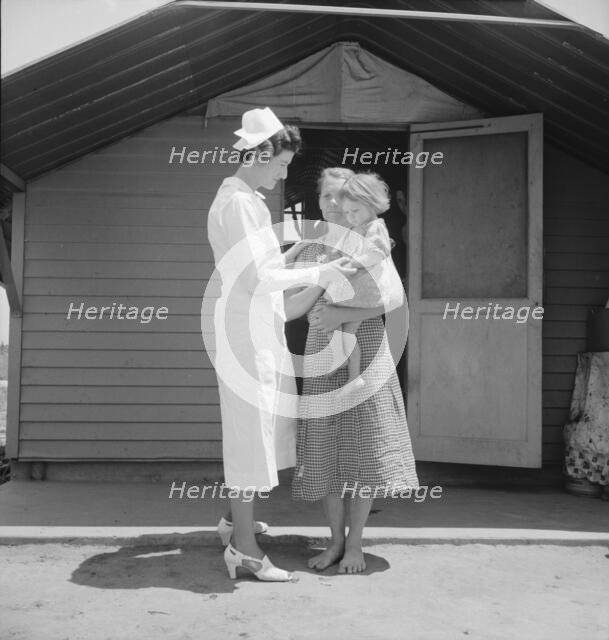 Resident nurse come to visit family, FSA camp, Farmersville, Tulare County, 1939. Creator: Dorothea Lange.