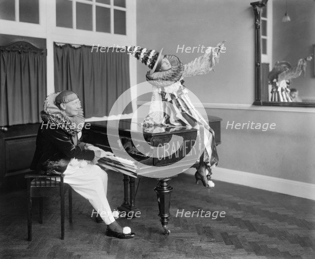 Two Pierrot clowns performing a routine with a piano, 1917. Artist: Bedford Lemere and Company.