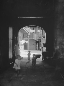 Children playing in an arched passageway, New Orleans, between 1920 and 1926. Creator: Arnold Genthe.