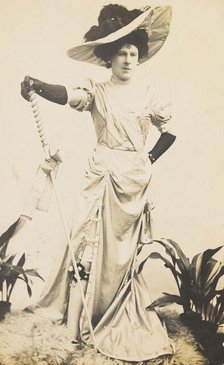 An man in drag is wearing a revealing dress and holding a staff, posing with his..., 1909. Creator: Unknown.