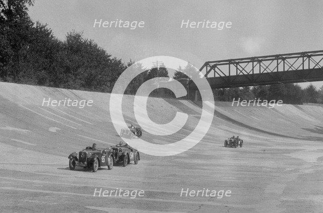 Singers of TW Fassett and Alf Langley and an MG racing at a MCC meeting, Brooklands, Surrey, 1933. Artist: Bill Brunell.