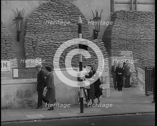 British People Walking by Heavily Sandbagged Buildings, 1940. Creator: British Pathe Ltd.